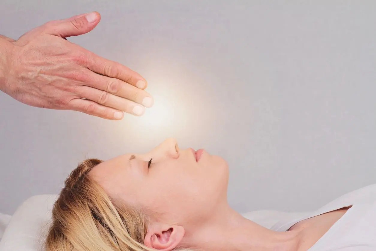 A woman is being given reiki by another person.